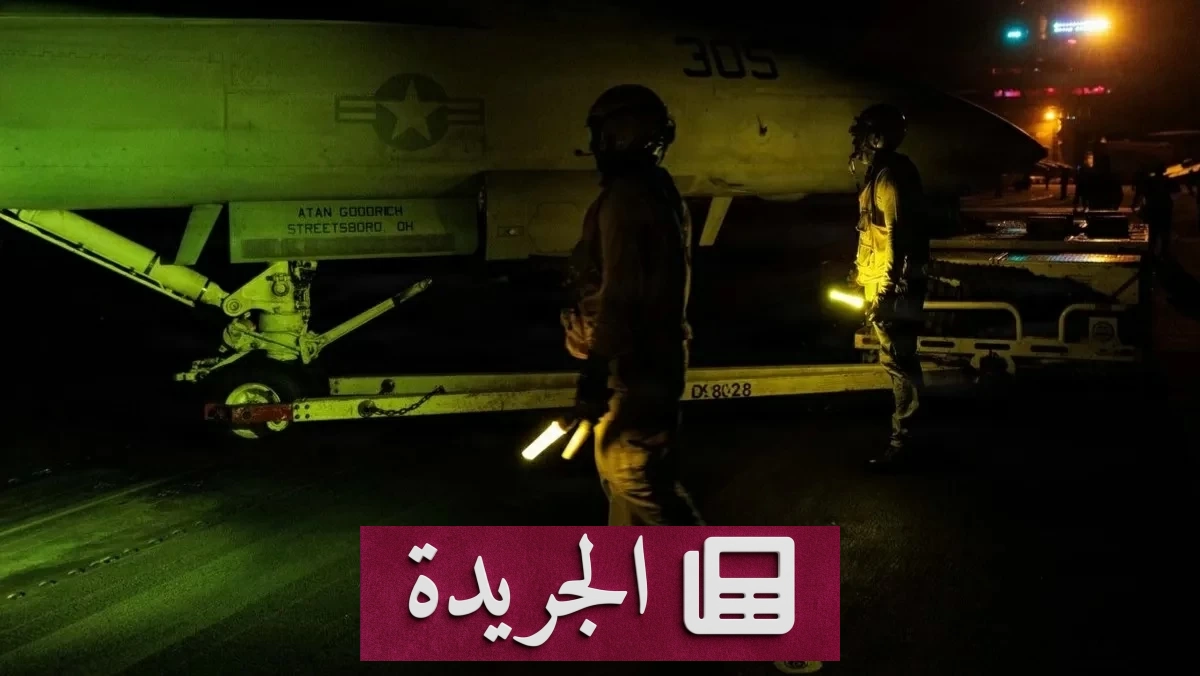 جنديان أمريكيان يقفان أمام مقاتلة على متن حاملة طائرات amid التوترات بين واشنطن وطهران
